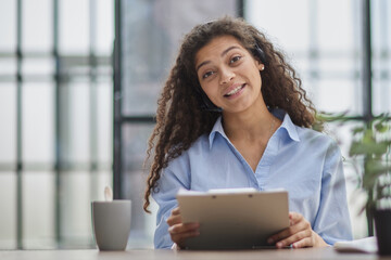 Brunette business woman using headset to communicate and advise people in customer service office.