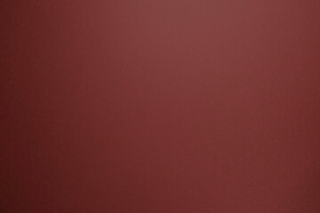 Empty maroon background lit professionally for horizontal copy space. Paper texture.