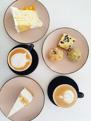 Flatlay of two coffees on cups and saucers plus cakes, cookies, and brownies on tiny plates. Food...