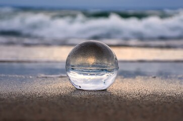 Fototapeta na wymiar Abstract holiday seaside idea. Sea landscape held in a glass ball with a blurred background.
