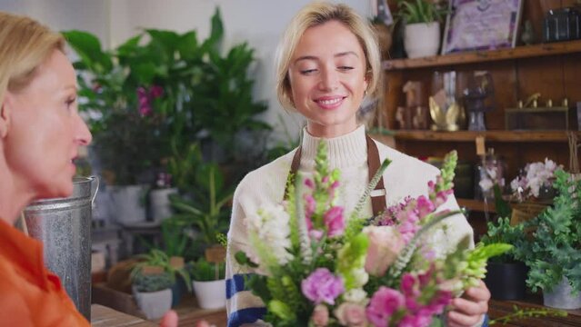 Mature woman buying bouquet of flowers in florists shop - shot in slow motion