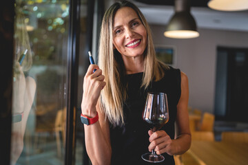 one woman with glass of red wine and electronic cigarette device