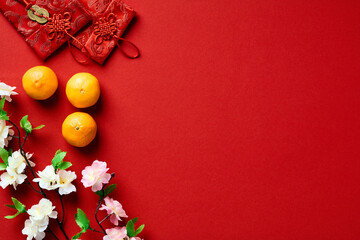 Happy Chinese New Year 2023 concept. Traditional red envelopes, tangerines, blossom flowers on red...