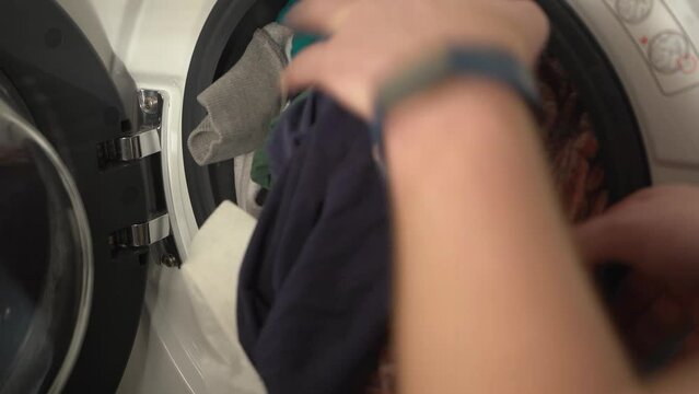 Closeup: Clothes pulled by Caucasian hands from white washing machine