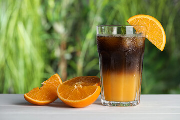Tasty refreshing drink with coffee and orange juice on white table against blurred background, space for text