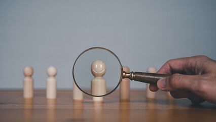 HRM or Human Resource Management, Magnifier glass focus to wooden people, manager, which is among staff  for human development recruitment leadership and customer target group concept.