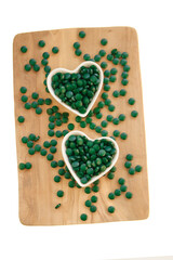 Spirulina algae tablets on a wooden board on a white background.Vitamins and dietary supplements.Super food .Food supplements for a healthy lifestyle