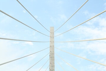 Fototapeta premium Beautiful modern bridge against blue cloudy sky, low angle view