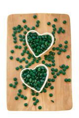 Spirulina algae tablets in cups in the shape of a heart on a board on a white background.Vitamins and dietary supplements.Super food .
