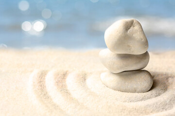 Fototapeta na wymiar Stack of white stones on sand with pattern, space for text. Zen, meditation, harmony