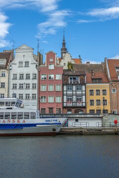 Vertical shot of the beautiful old town buildings and water trams at the river in Gdansk, Poland