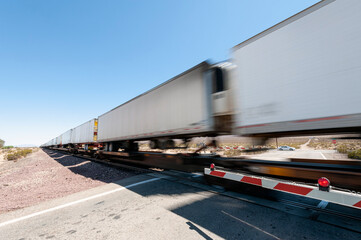 Fototapeta na wymiar Train cars speed passed a railroad crossing in the California desert
