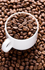 Roasted coffee beans in a cup, on dark background, close-up image, space for text