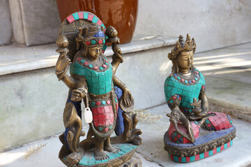  Bronze statuettes of gods decorated with gems stand on marble steps near a souvenir shop in...