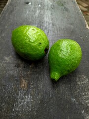 green guava fruit, on a dark brown wooden board in the morning