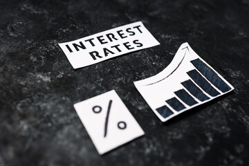 Interest rates text with percentage symbol and chart with stats increasing on dark background, economic struggles after the pandemic