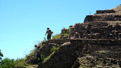 Worker mowing the slope of a pyramid at Monte Alban, in Oaxaca, Mexico