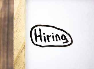 Hiring - concept text on a white board written in black marker.