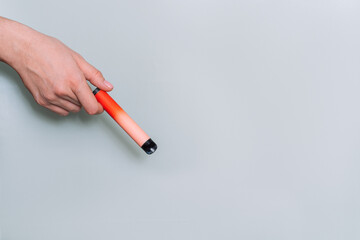 Electronic cigarette in female hand against green background.