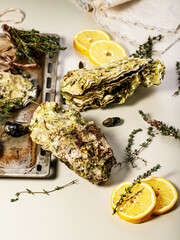 Giant fresh Pacific oysters on a light background. Lemon and oregano. Selective focus. Vertical shot