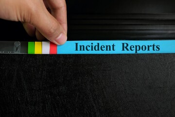 Hand picking incident report file in black binder folder. Corporate business concept.