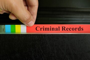 Hand picking criminal records file in black binder folder. Police record concept.
