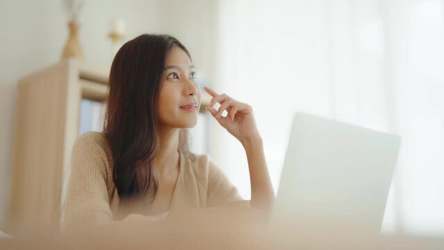 Young asian woman working on computer laptop on desk in living room at home