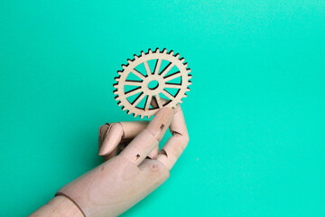 wooden hand holding gear teeth engineering concept on light blue background. The concept of...
