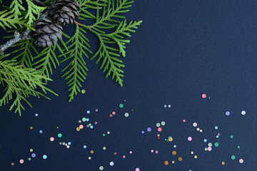 Cypress branches, pine cones and multicolor confetti on black background. Winter holiday concept....