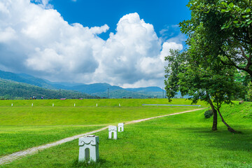 Fototapeta na wymiar A public place leisure travel wide lawn and big tree landscape at Park to relax with in nature forest Mountain views spring cloudy sky background with white cloud in Chiang Mai University.