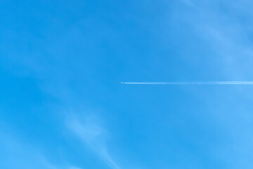 Jet aircraft flying on the high altitude against the backdrop of a clear blue sky. Airplane with two condensation trail on clouds and sky. View of airplane trace among the clouds and clear blue sky.
