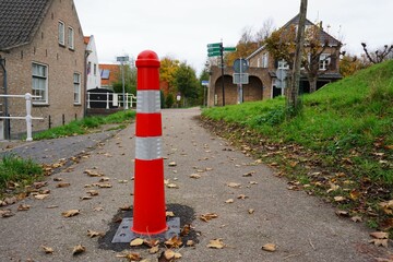 Fototapeta na wymiar Red and white dividing post. Road barrier to separate the footpath from cyclists who belong on the bike path. Reflective and striking color.