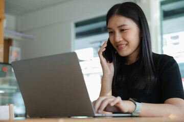 Young businesswoman talking on smartphone with her work at her desk in office, Phone communication and startup business concept.