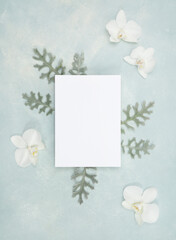 Floral flat lay with blank stationery card and fresh white orchid flowers and botanical elements
