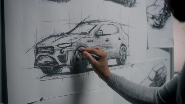Automotive african american male designer drawing sketch blueprint with marker on whiteboard, developing new generation electric car design. He working in car design development modern studio.