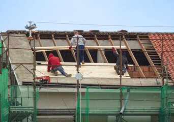 Fototapeta premium men working on the roof of a building for thermal insulation work