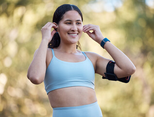 Woman, fitness and music with an athlete wearing earphones for motivation songs before a exercise workout in nature. Working out, running and athletic female streaming a podcast on her phone outside