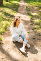 Photo of young woman in white shirt sitting in forest and having a relax time