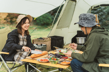 秋冬のキャンプ場で料理を作るアジア人のカップルキャンパー
