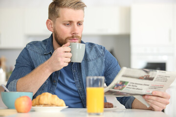 handsome young man with cup of coffee and newspaper