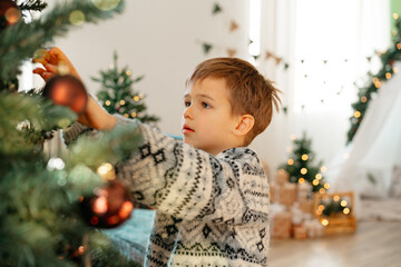 Beautiful smiling little boy standing near Christmas tree