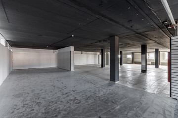 Empty retail space with a black ceiling and a dirty floor, immediately after repair