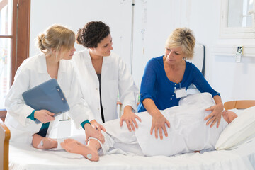 nurses practicing how to roll a patient with dummy