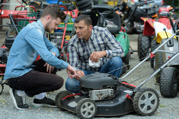 Fototapeta na wymiar consultant shows a customer lawn mower in garden tools store