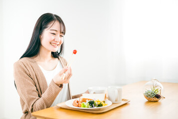 朝食で美味しそうに笑顔でトーストされた食パンを食べる日本人女性
