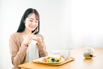 Obraz na płótnie Canvas 朝食で美味しそうに笑顔でトーストされた食パンを食べる日本人女性 