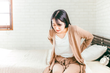 ベッドルームで腰痛・ヘルニアなどの腰の病気に悩む日本人女性
