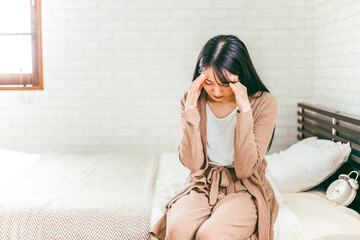 ベッドルームで頭痛やうつ病に悩む日本人女性
