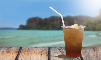 Brown wooden table and iced peach tea with background sea view.