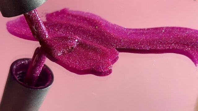 Pink gel nail polish on a pink background. Brush movement. 